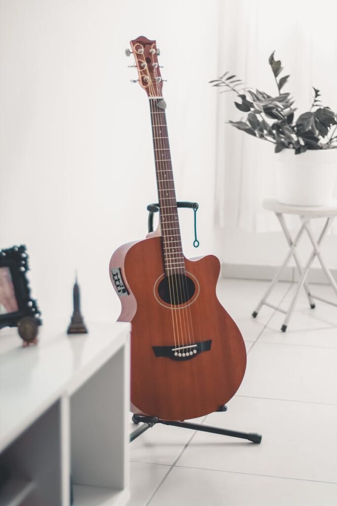 A classic acoustic guitar stands elegantly in a bright, minimalist indoor setting, surrounded by modern decor.